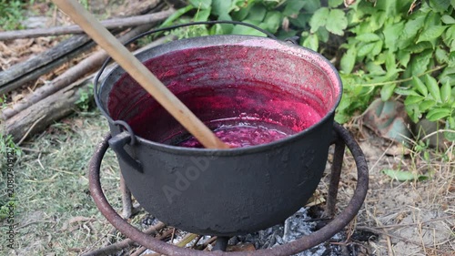 Cooking berry jam in a large cauldron over an open fire outdoors