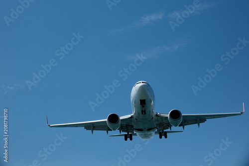 White passenger plane on final approach for landing against a blue sky