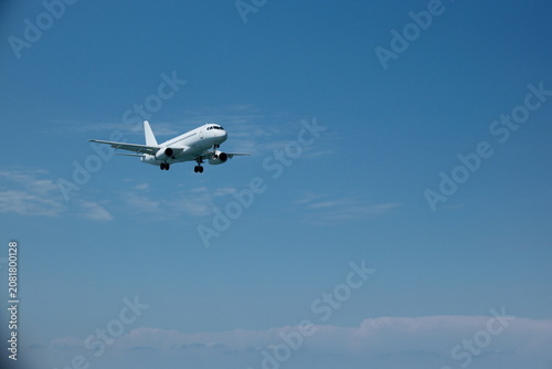White passenger plane on final approach for landing against a blue sky