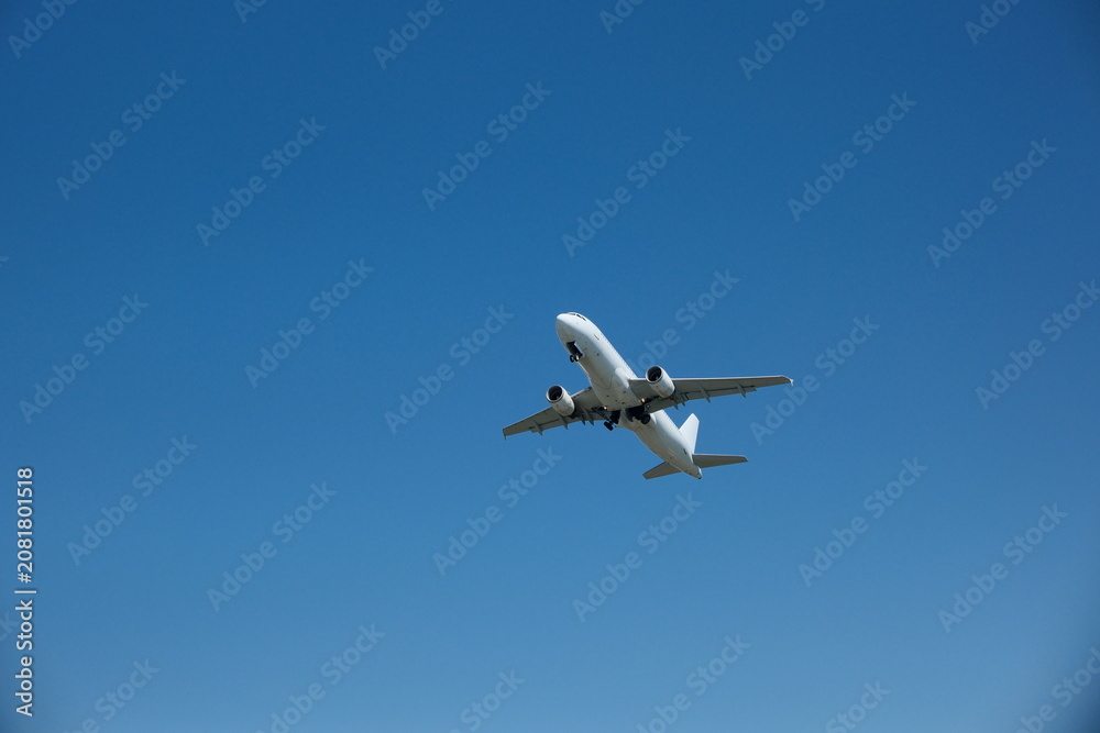 Obraz premium White passenger airplane taking off and gaining altitude against a blue sky