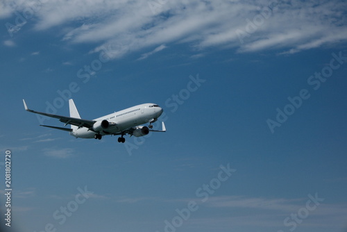 White passenger plane on final approach for landing against a blue sky
