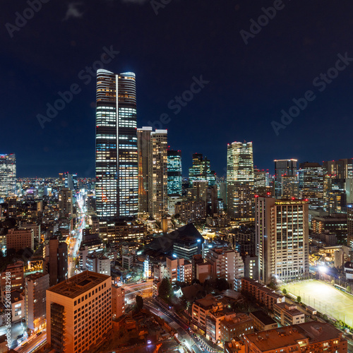 Aerial night view of the illuminated Tokyo cityscape and skyline with dense buildings.