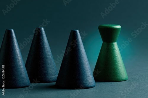 Green wooden pawn standing apart from dark blue cones for leadership concept background and teamwork poster design