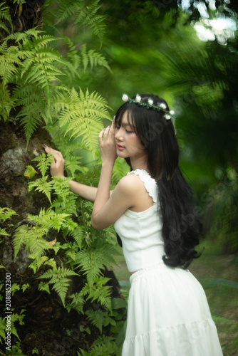 A beautiful young woman among the fern leaves in the forest.