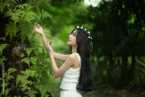A beautiful young woman among the fern leaves in the forest.