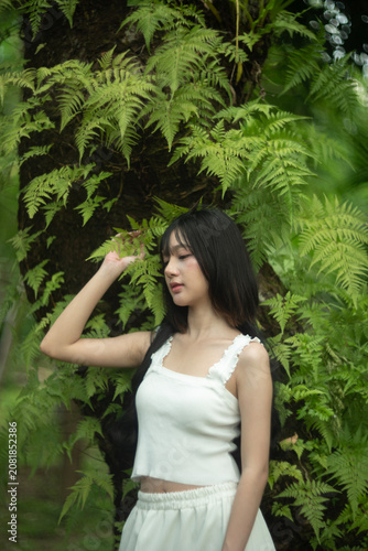 A beautiful young woman among the fern leaves in the forest.