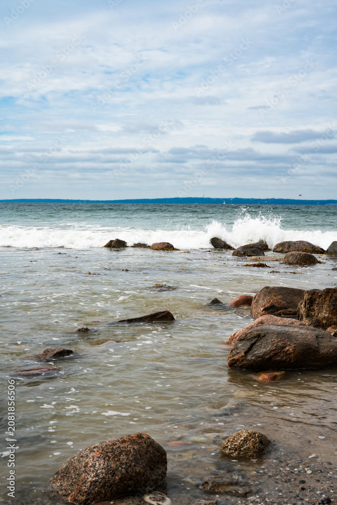 Fototapeta premium Rocky east coast of denmark with crashing waves. Vertical natur background.