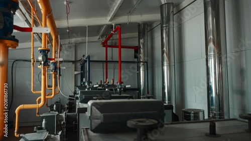 Modern gas boiler room interior with color coded piping, stainless exhaust flues, utility lines, industrial controls, heating equipment, reflective metal surfaces, organized technical layout across