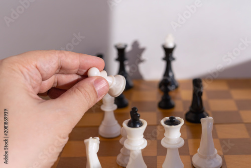 Canvas Print Hand moving white chess pawn to attack opponent pieces on chessboard, business takeover concept