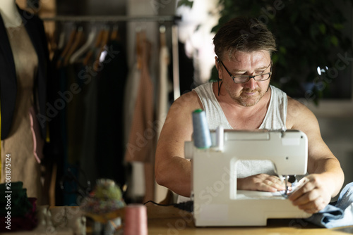 Photos Middle-aged male dressmaker working with sewing-machine at night