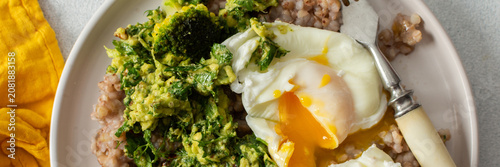 Schilderij op canvas A healthy breakfast bowl features green buckwheat topped with pesto, steamed broccoli, and poached eggs