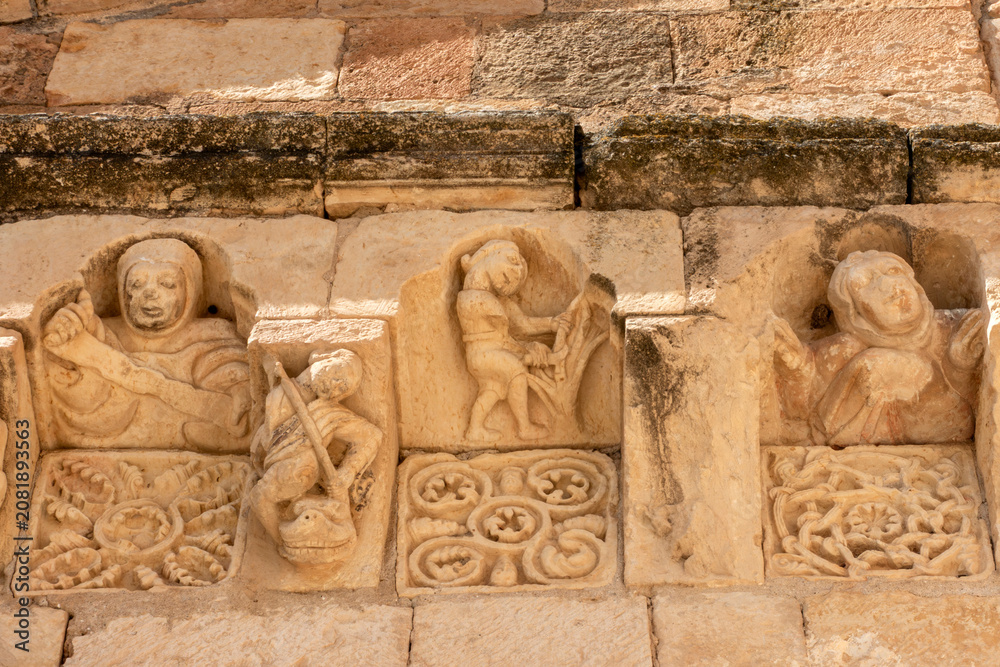 Fototapeta premium Romanesque Carved Corbels and Metopes with Human Figures from the 12th to 13th Century Cornice of the Church of San Miguel Arcangel in Sotosalbos, Segovia, Castile and Leon, Spain