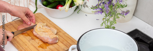 Φωτογραφία Someone is cutting a chicken breast on a wooden board in a kitchen