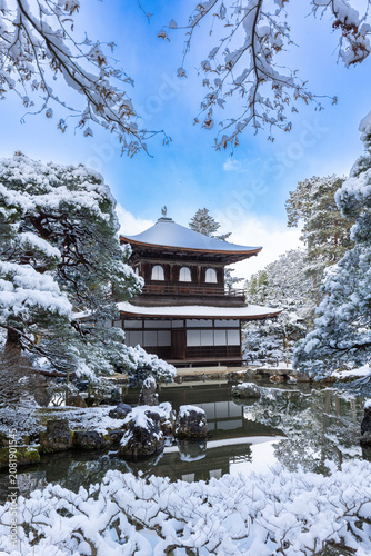 Foto Stunning vertical view of a historic Japanese temple pavilion reflected in a pond surrounded by snow-covered trees, Kyoto
