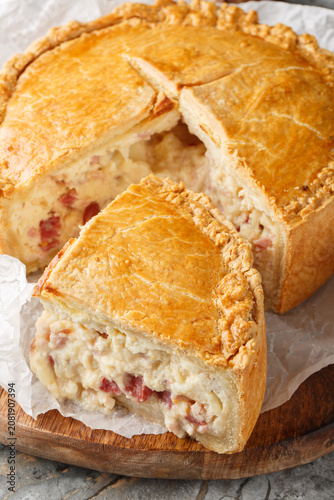 Pizza Gaina or Pizza Rustica is an Italian easter pie with mortadella, salami, mozzarella, and pecorino romano closeup on the wooden board. Vertical
