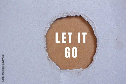 Tablou pe pânză Ripped gray paper showing a hole with the message let it go on a brown backgroun