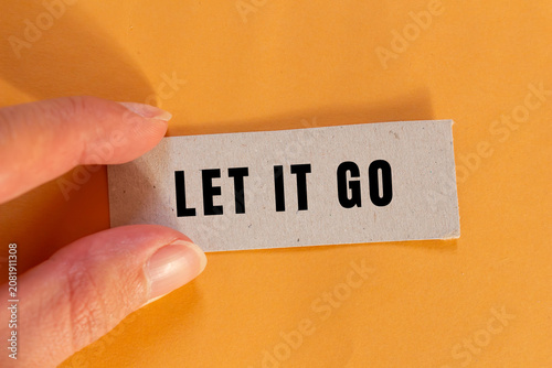 Tablou pe pânză Hand holding a paper card with let it go text, symbolizing release, acceptance,