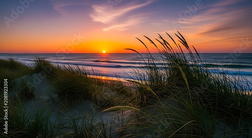 Breathtaking golden sunset over serene coastal dunes, with tall grass silhouetted against a vibrant sky, reflecting fiery hues on the peaceful ocean waves