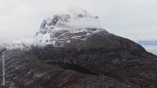 Aerial Cinematic View of Giant Snowy Mountain Peak and Dark Glacial Lake