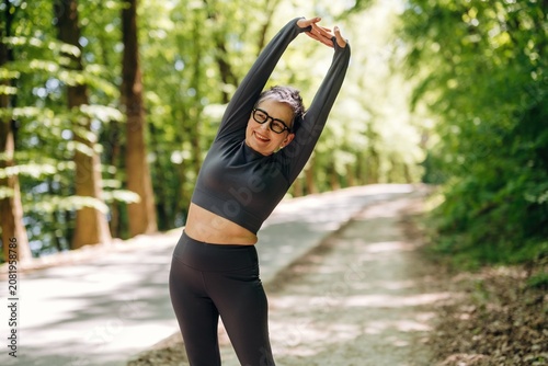 Принти на полотні Female fitness enthusiast in black activewear stretches her arms overhead on a f