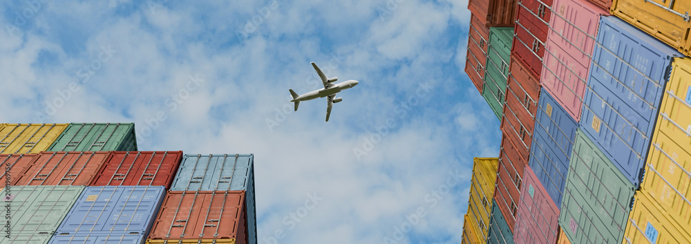 Naklejka premium Airplane Flying Over Colorful Stacked Shipping Containers at Cargo Port, Low Angle View of Global Logistics