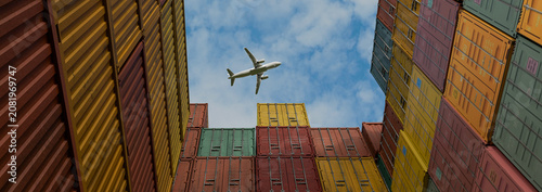 Quadro su tela Airplane Flying Over Stacked Colorful Shipping Containers at Cargo Port, Global