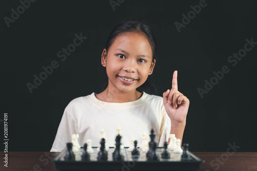 Canvastavla Thoughtful Asian girl pointing fingers at her temples while analyzing a chess game on a black background