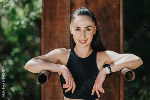 Foto A fit young woman smiles while leaning on parallel bars after exercising outdoors