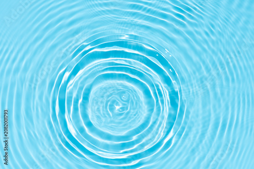 Blue water with ripples on the surface. Defocus blurred transparent blue colored clear calm water surface texture with splashes and bubbles. Water waves with shining pattern texture background.