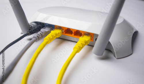 Фотография Close-up view of a white wireless router back panel with two yellow Ethernet cab