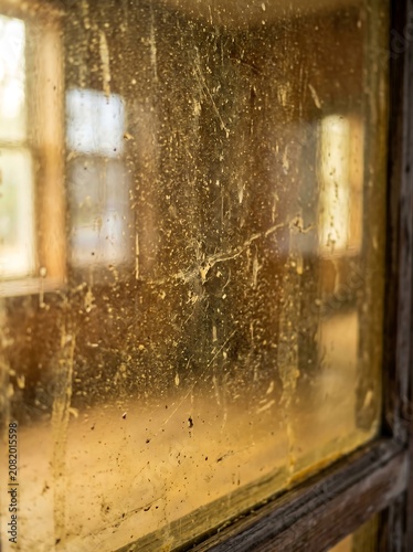 Close-up of a very dirty and stained glass window in an old building.