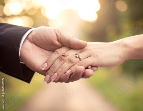 Couple holding hands with engagement ring outdoors sunlight