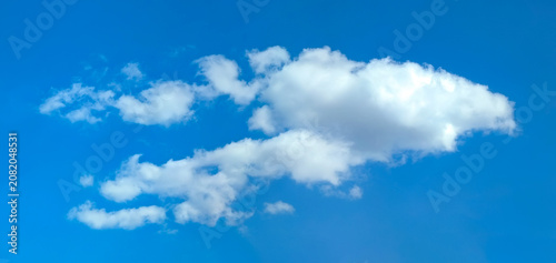 Isolated cascading cloud floating in the wind against blue sky. Big glowing clouds spreading on the deep blue sky sunny day. Nature concept background. Elegant landscape image