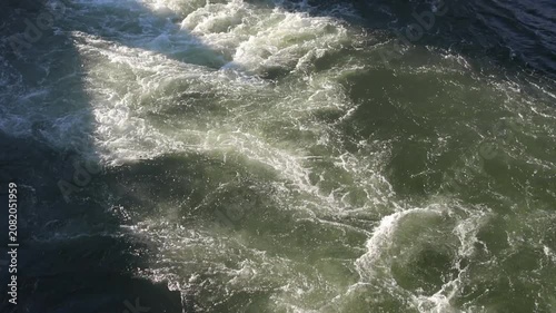 White foam wake of a moving boat churning dark water