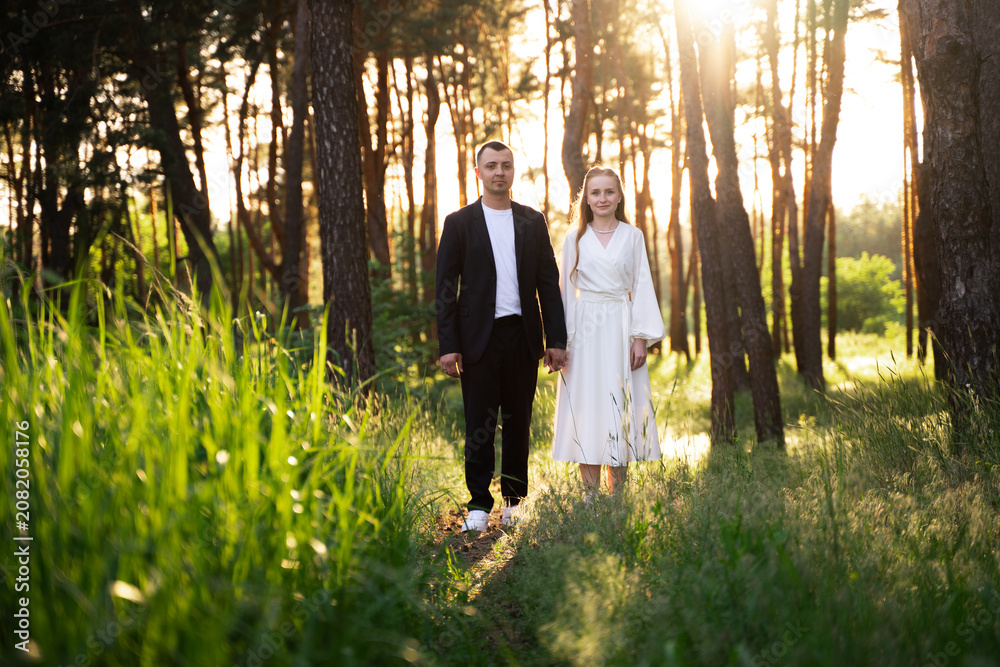 Fototapeta premium Couple holding hands in a sun-drenched forest during golden hour