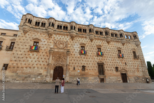 Guadalajara, Spain. Low angle view of the fifteenth century Palacio del Infantado with Isabelline Gothic facade with diamond-tipped stones, a plateresque portal, and LGBT pride flags from balconies