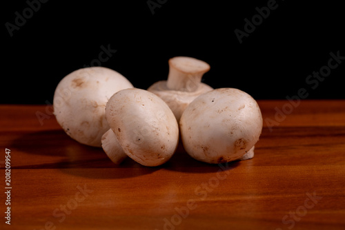 Fresh white button mushrooms (champignon mushrooms) arranged on a wooden cutting board. Natural organic ingredients for healthy cooking, meal preparation, vegetarian recipes.