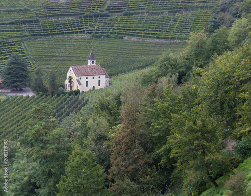 Idyllische St. Valentin Kirche inmitten von grünen terrassierten Weinbergen in Meran Südtirol