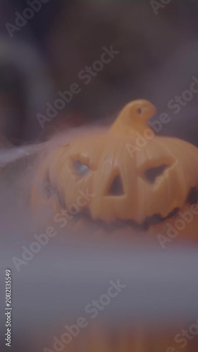 Close-up cinematic footage of jack o lantern partially hidden behind thick smoke, creating a dramatic Halloween horror atmosphere with shallow depth of field.
