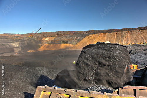 Foto A bulldozer filling a mining truck with coal, creating huge coal dust clouds