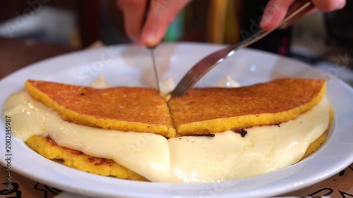 Cutting Traditional Venezuelan Cachapa with a Knife, Melted Cheese Close-up