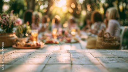 Blurred summer garden brunch lifestyle scene with pale stone tabletop, flowers, drinks and golden sunlight for social copy space