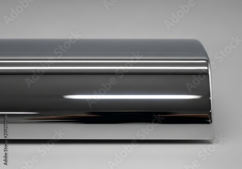 Polished chrome metal bar with bright reflections on grey background.