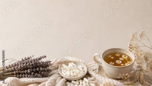 Herbal tea and supplement capsules with lavender wellness background
