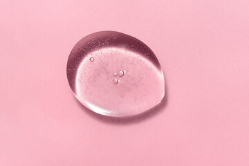 Transparent pink cosmetic serum texture with bubble on pink background