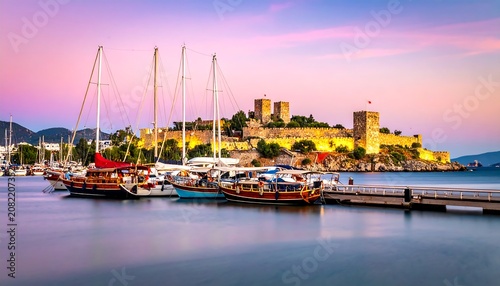 A serene harbor with boats and a majestic castle at sunset