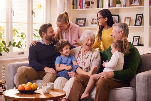 Famille multigénérationnelle réunie dans un salon, grands-parents, parents et petits-enfants partageant un moment de bonheur