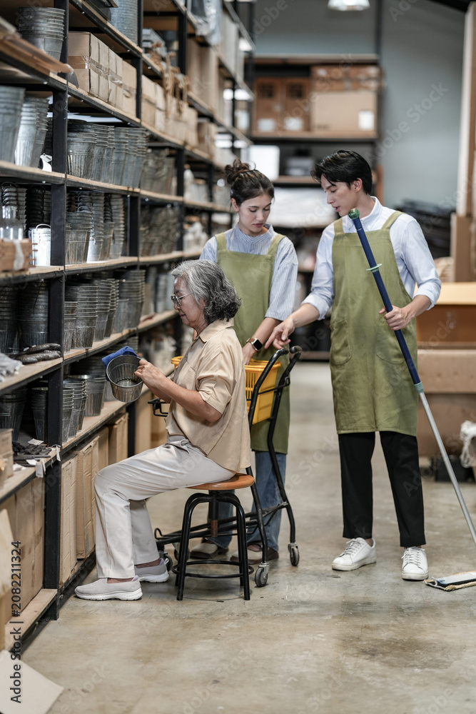 Fototapeta premium A senior woman entrepreneur and her young team pointing out a product on the shelf during a walkthrough in a handmade goods storeroom. Capturing modern small business owners at work.
