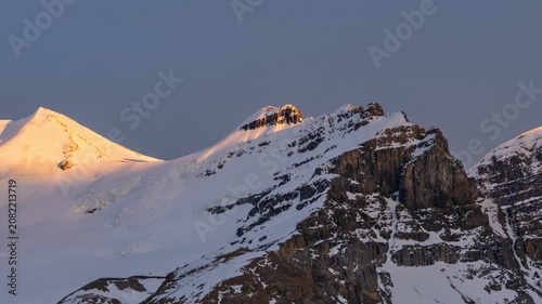 Timelapse of golden sunlight moving across snowy mountain peaks in Jasper National Park, Alberta, Canada