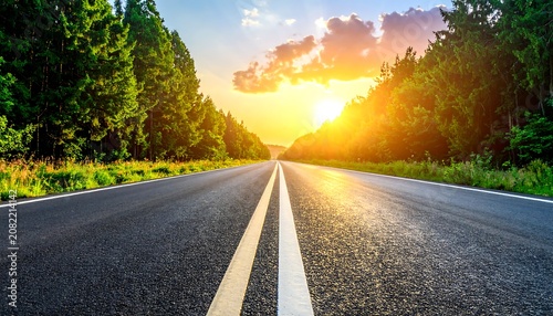 A serene highway stretching into the distance, lined with lush greenery on both sides, under a vibrant sunset sky
